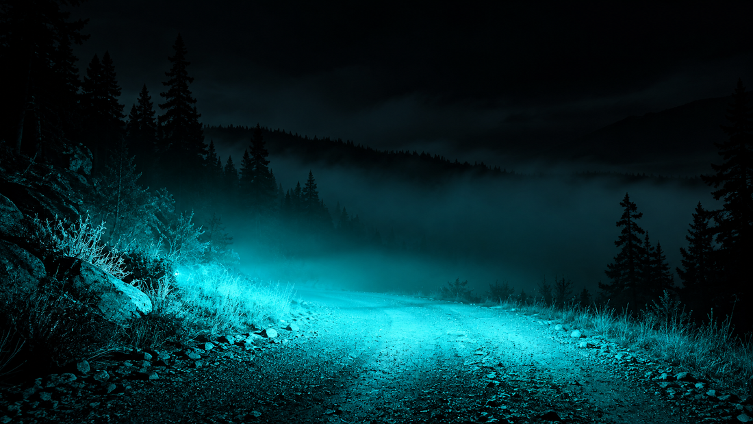 Wide cyan beam sweeping low across a foggy gravel path at night