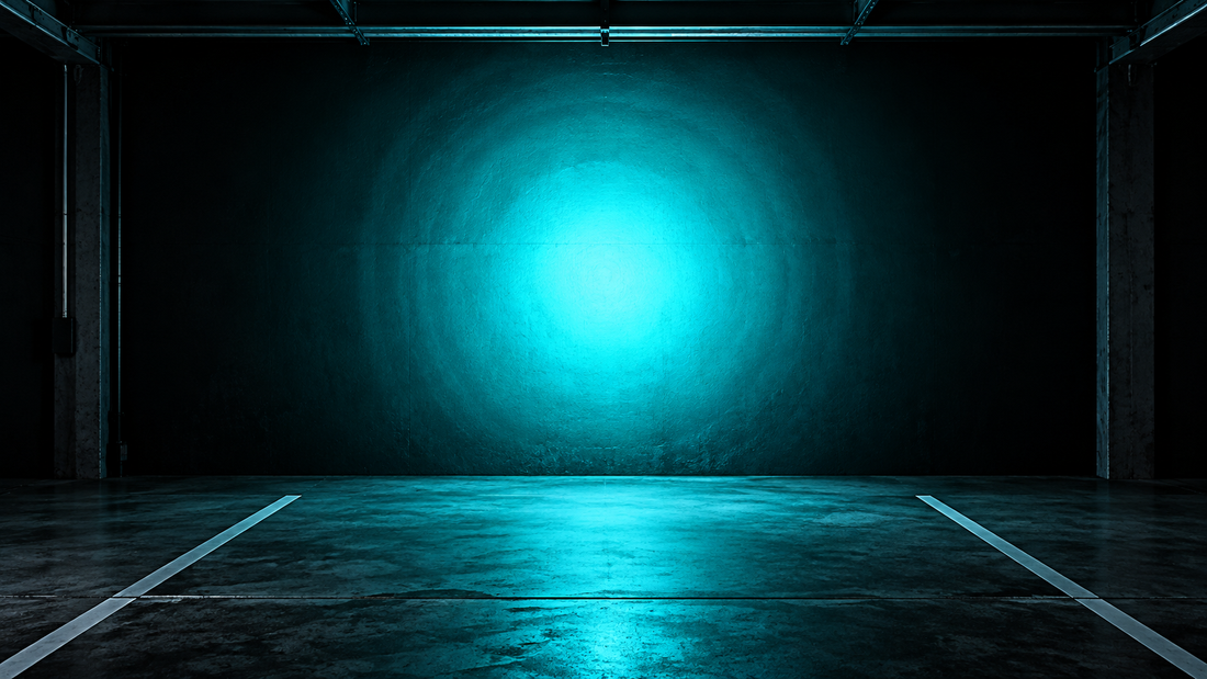 Round vivid cyan light hotspot on a dark garage wall with soft spill