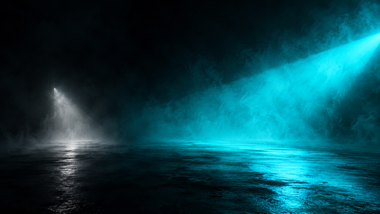 A weak pale-white light cone beside a wide vivid cyan beam in dark fog